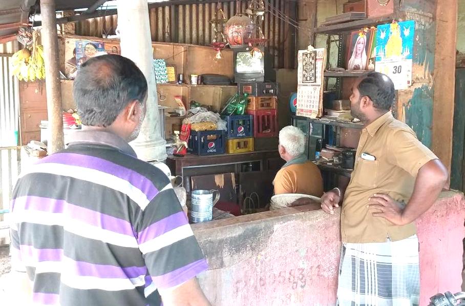 Men stop to watch ICII's TV broadcast at a shop in a village in India.